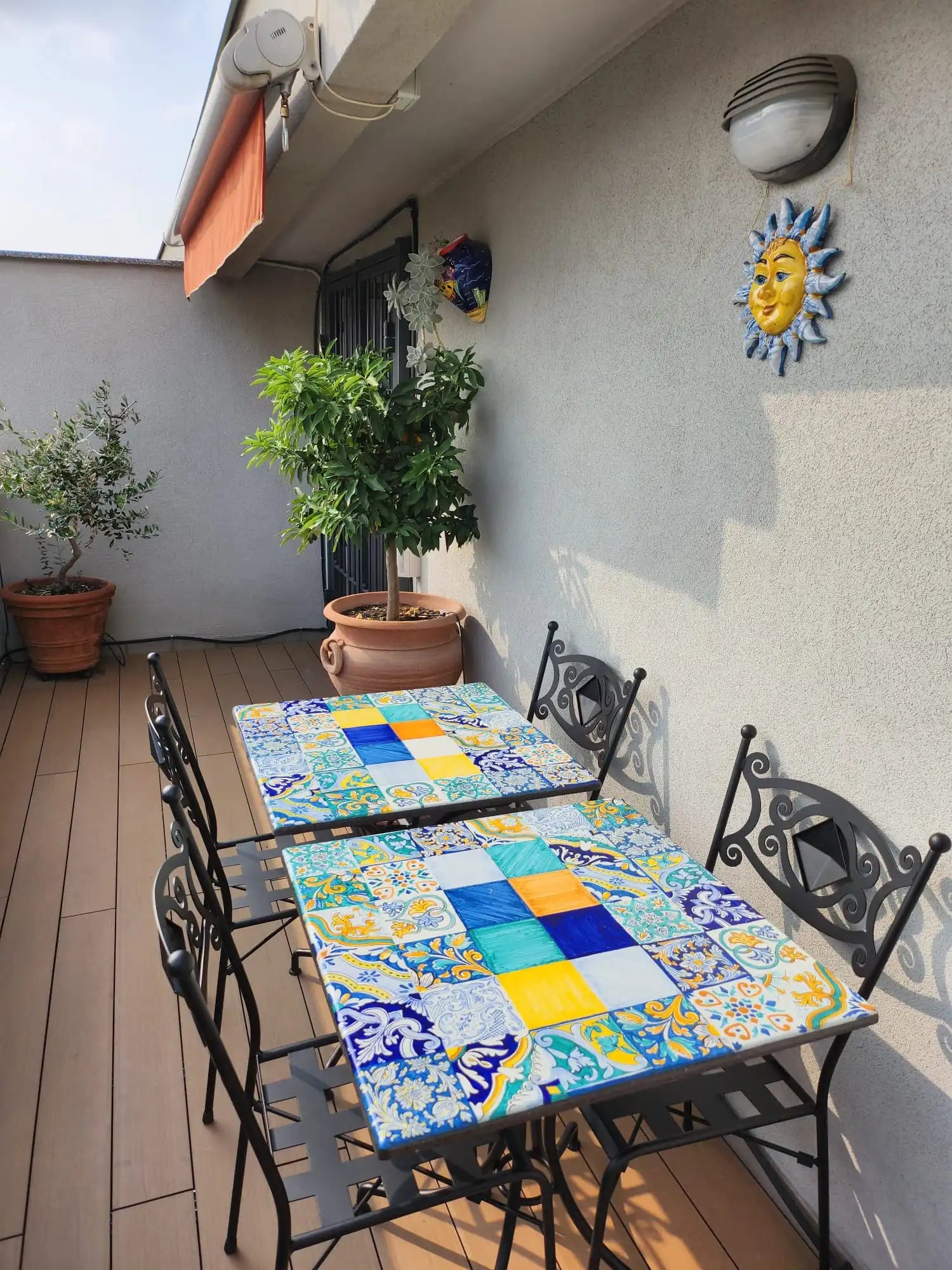 Tavolo da patio in ferro battuto con top in mosaico di piastrelle di ceramica colorate e sedie coordinate.