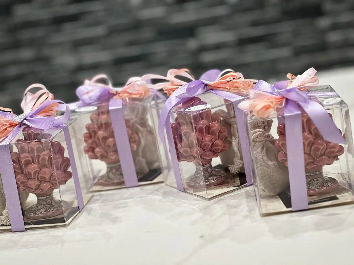 Scatole regalo trasparenti con dolcetti di cioccolato legati con nastri viola e pesca.