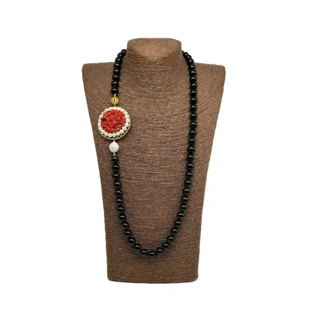 Collana di perle nere con un ciondolo circolare decorativo rosso e bianco.